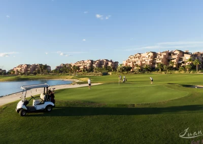 buen tiempo golf unos jugadores estan en el green junto a un lago