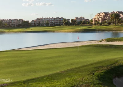 Fotografía terrestre de campo de golf en la costa mediterránea con bandera, green y lago